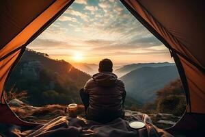 posteriore Visualizza di viaggiatore uomo seduta al di fuori il tenda e godendo bellissimo Visualizza su tramonto o Alba. campeggio, viaggiare, vacanza concetto. generativo ai foto