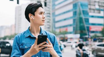 giovane uomo asiatico che cammina e usa lo smartphone per strada