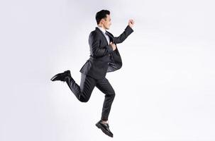giovane uomo d'affari asiatico che salta su sfondo bianco foto