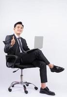 giovane uomo d'affari asiatico seduto su una sedia su sfondo bianco? foto