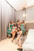 un' gruppo di asiatico donne nel affascinante e lussuoso Abiti siamo seduta su il divano con loro amici dopo partying foto