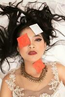 un asiatico donna con un' oro collana cascate addormentato con un' preservativo involucro su sua viso nel un' Hotel foto