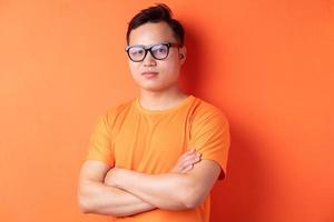 uomo asiatico con le braccia incrociate su sfondo arancione