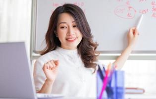 insegnante femminile asiatica che insegna online a casa foto