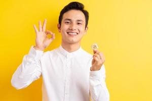uomo d'affari asiatico che tiene bitcoin in mano wite faccia felice