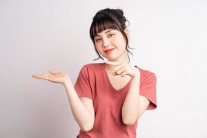 giovane donna asiatica in posa su sfondo bianco, usando il dito per indicare e mostrare, gesto della mano