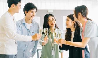 gli uomini d'affari asiatici brindano ai loro bicchieri celebrando i risultati foto