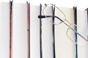 occhiali e libri spessi su sfondo bianco