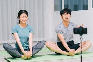 il personal trainer asiatico sta guidando gli studenti nello yoga e nella registrazione video per insegnare lo yoga online foto