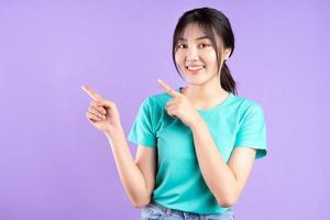 giovane ragazza asiatica in camicia ciano in posa su sfondo viola