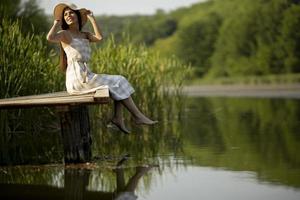 rilassante giovane donna sul molo di legno al lago foto