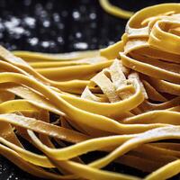 vicino su di un' crudo asciutto italiano pasta fettuccine su nero di legno tavolo. ai generativo foto