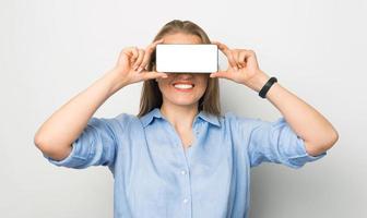 foto di una donna d'affari sorridente che tiene in mano uno smartphone con uno schermo bianco sugli occhi
