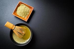 tazza di tè verde matcha caldo con polvere di tè verde e frusta di bambù foto