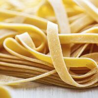 vicino su di un' crudo asciutto italiano pasta fettuccine su bianca di legno tavolo. ai generativo foto