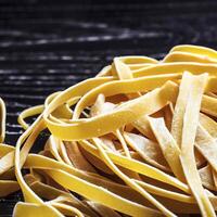 vicino su di un' crudo asciutto italiano pasta fettuccine su nero di legno tavolo. ai generativo foto