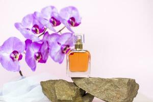 un' profumo bottiglia sta su un' pietra contro un' sfondo di bellissimo orchidee. elegante aspetto esteriore, disposizione, personalità. striscione, un' posto per il testo. foto