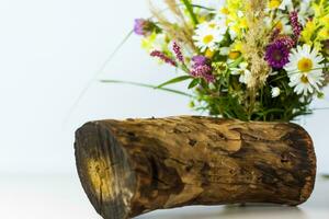 un' asciutto ceppo, albero abbaiare e un' mazzo di selvaggio fiori nel un' piccolo bicchiere vaso. elegante aspetto esteriore, disposizione, personalità. foto