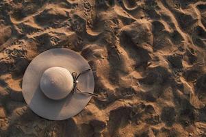 sfondo spiaggia sabbiosa con cappello estivo alla luce del sole foto