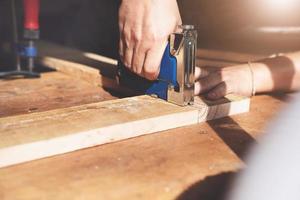 falegnameria dell'imprenditore che tiene una graffatrice per assemblare i pezzi di legno come ordinato dal cliente. foto