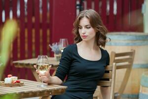 bellissimo giovane donna potabile bianca vino su il terrazza di un' ristorante foto