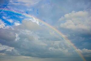 bellissimo multicolore arcobaleno dopo pioggia su blu cielo e bianca nuvole nel il mezzo di un' villaggio nel un' Comunità nel Tailandia foto