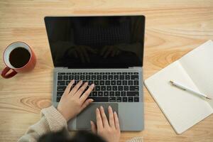 superiore Visualizza. asiatico libero professionista donna indossare bicchieri digitando su tastiera e Lavorando il computer portatile su tavolo a casa. imprenditore donna Lavorando per sua attività commerciale a vivente camera casa. attività commerciale opera casa concetto. foto