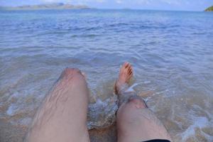 l'uomo è sulla spiaggia e i piedi nel mare foto