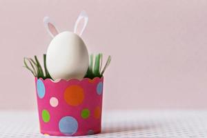 uovo di gallina bianco con orecchie da coniglio in un vassoio di carta rosa ecologico, scatola. felice vacanza di pasqua concetto. foto