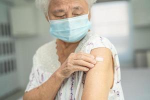 anziana donna anziana asiatica che indossa una maschera facciale che riceve il vaccino contro il covid-19 o il coronavirus dal medico fa l'iniezione.