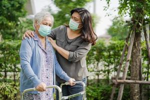 donna anziana asiatica anziana o anziana cammina con il deambulatore e indossa una maschera facciale per proteggere l'infezione di sicurezza covid-19 coronavirus. foto