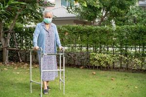 la donna anziana o anziana asiatica cammina con il deambulatore e indossa una maschera facciale per proteggere l'infezione di sicurezza e uccidere il nuovo virus covid-19 del coronavirus.