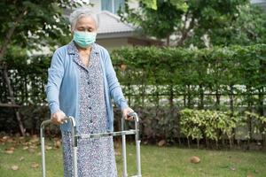 donna anziana asiatica anziana o anziana che indossa una maschera facciale nuova normalità nel parco per proteggere la sicurezza dall'infezione covid-19 coronavirus. foto