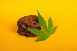 biscotti alla cannabis e marijuana a foglia verde su sfondo giallo, trattamento della marijuana medica per uso alimentare foto