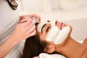 estetica applicando una maschera al viso di una bella donna foto