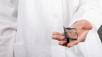 oftalmologo che tiene gli occhiali in mano ravvicinata, optometrista professionista offre occhiali al paziente foto