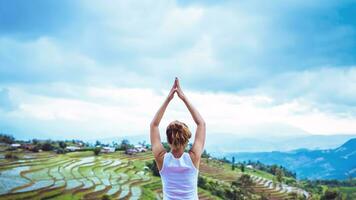 donna asiatica rilassarsi in vacanza. gioca se lo yoga. sul balcone paesaggio campo naturale foto