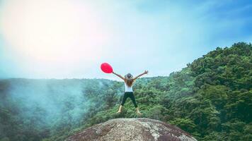 asiatico donne viaggio natura. viaggio relax. palloncini nel mano salto. toccare nebbia. foto