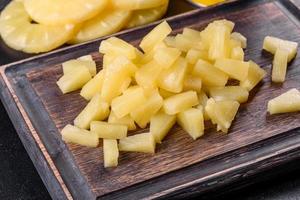 ananas in scatola con pezzi su un tagliere di legno foto