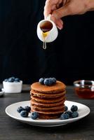 pila di pancake al cioccolato con mirtillo e miele su un piatto foto