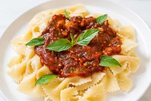 Farfalle con basilico e aglio in salsa di pomodoro - salsa italiana foto