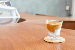 bicchiere di caffè sporco, o latte freddo condito con un caffè espresso caldo, in una caffetteria foto