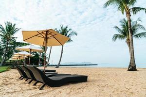sedia a sdraio vuota con palme sulla spiaggia con sfondo mare sea foto