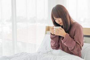 donna asiatica che beve caffè a letto la mattina?