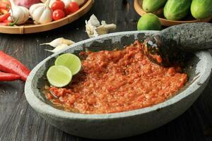 Sambal Tomat o speziato pomodoro incolla su pietra mortaio e pestello foto