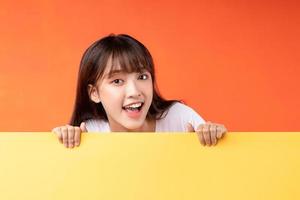 giovane ragazza asiatica che si sovrappone a sfondo giallo su sfondo arancione