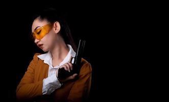 asea donna che indossa un abito giallo una mano che tiene una pistola pistola a sfondo nero foto