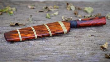 coltello personalizzato o enep nel fodero in legno naturale sul vecchio sfondo del tavolo fatto a mano in thailandia
