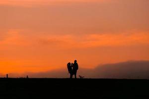 silhouette di una coppia che fa trekking in montagna con un tramonto foto