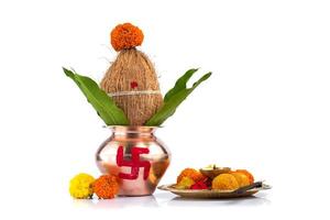 kalash di rame con cocco e foglia di mango e pooja thali con diya, kumkum e dolci con decorazione floreale su sfondo bianco. essenziale nella puja indù. foto